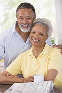 Couple relaxing with a newspaper smiling