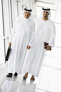 Two businessmen walking in a corridor smiling (high key/selective focus)