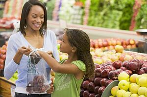 Woman and daughter shopping for apples at a grocery store