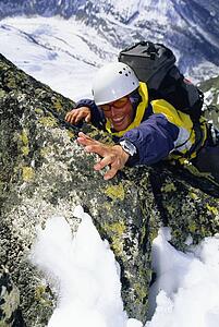 Mountain climber coming up snowy mountain smiling (selective focus)