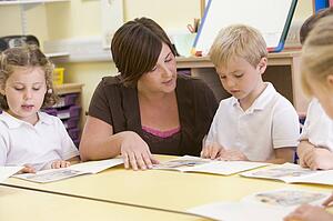 Students in class with teacher reading (selective focus)