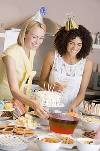 Two women at party setting out food smiling