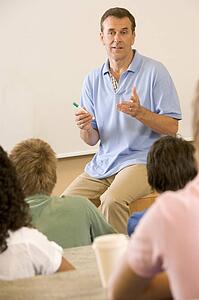 Teacher giving lecture to students in classroom (selective focus)