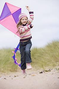 Young girl on beach with kite smiling