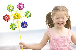 Young girl at beach with toy windmill smiling