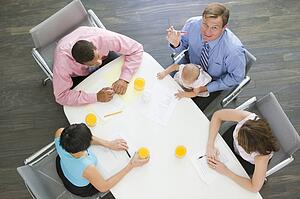 Four businesspeople in boardroom with one holding a baby