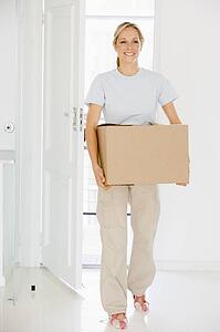 Woman with box moving into new home smiling