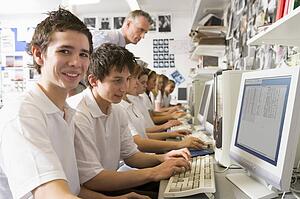 Students working on computer workstations with teacher