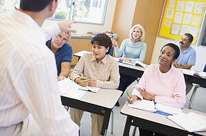 Adult students in class with teacher (selective focus)