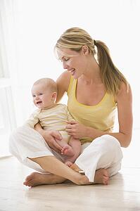 Mother and baby sitting indoors smiling