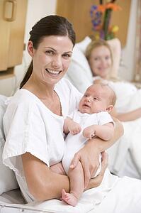 New mother with baby in hospital smiling
