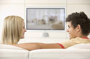 Couple in living room watching television smiling