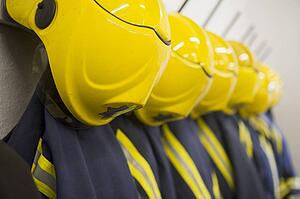 Line of firefighting uniforms hanging neatly on wall hooks (depth of field)