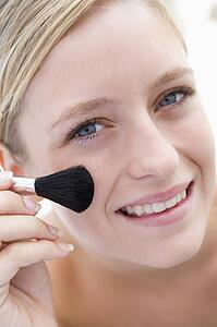 Woman with makeup brush smiling