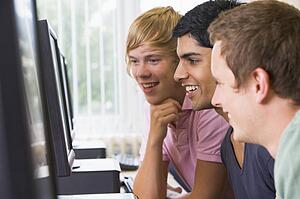 Three men sitting at a computer terminal (high key)