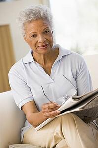 Woman with a newspaper holding eyeglasses