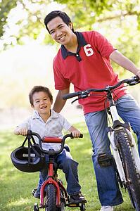 Man and young boy on bikes outdoors smiling
