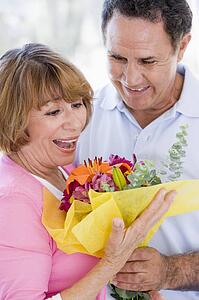Husband and wife holding flowers and smiling