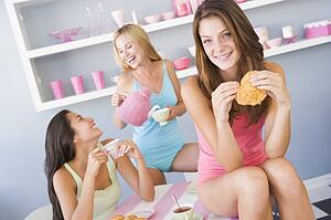 Three young woman sitting at a table having tea and a snack