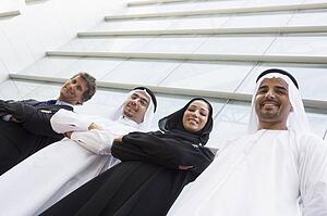 Four businesspeople standing outdoors by building smiling (selective focus)