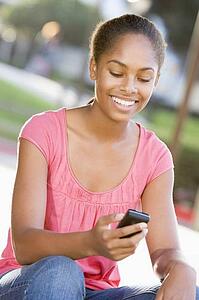 Teenage Girl Sitting Outdoors Using Mobile Phone