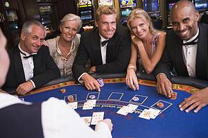 Five people in casino playing blackjack and smiling (selective focus)
