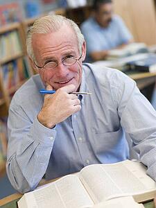 Man in library with pen and book (selective focus)