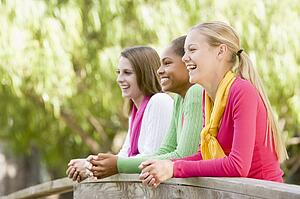 Teenage Girls Leaning On Wooden Railing