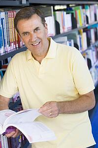 Man in library holding book (depth of field)