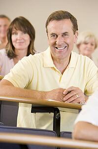 Man sitting in adult classroom with students in background (selective focus)