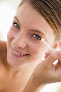 Woman with eyeshadow applicator smiling