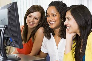 Three women sitting at a computer terminal (high key)