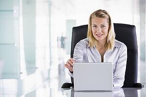 Businesswoman sitting in office with laptop smiling