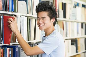 Man in library pulling book off a shelf (depth of field)