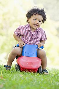 Young boy playing on toy with wheels outdoors