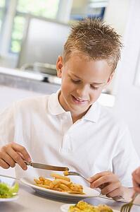Student in cafeteria eating lunch (selective focus)