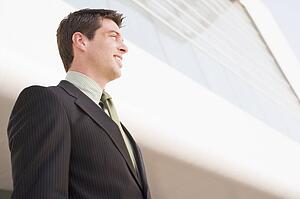 Businessman standing outdoors by building smiling