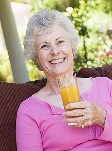 Senior woman sitting outdoors with a glass of orange juice