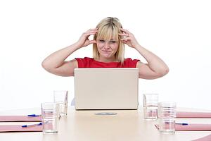 Businesswoman sitting in boardroom with laptop looking frustrated
