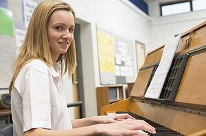 Female student learning piano in classroom