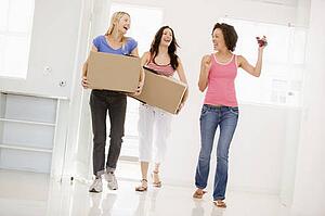Three girl friends moving into new home smiling