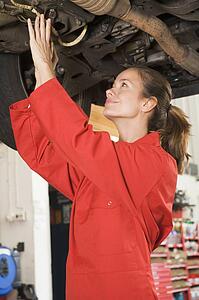 Mechanic working under car smiling