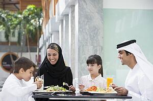 Family at restaurant eating and smiling (selective focus)