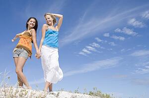 Two young women posing on a sand hill