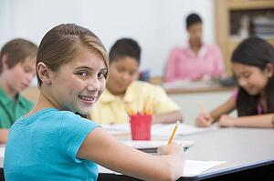 Students in class taking notes with teacher in background (selective focus)