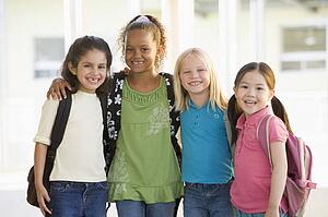 Four students outside school standing together smiling (high key)