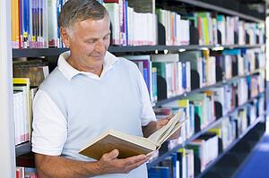 Man in library reading book (depth of field)