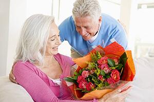 Husband giving wife flowers and smiling