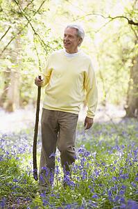 Man walking outdoors with walking stick smiling