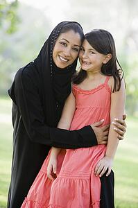 Woman and young girl outdoors in a park smiling (selective focus)